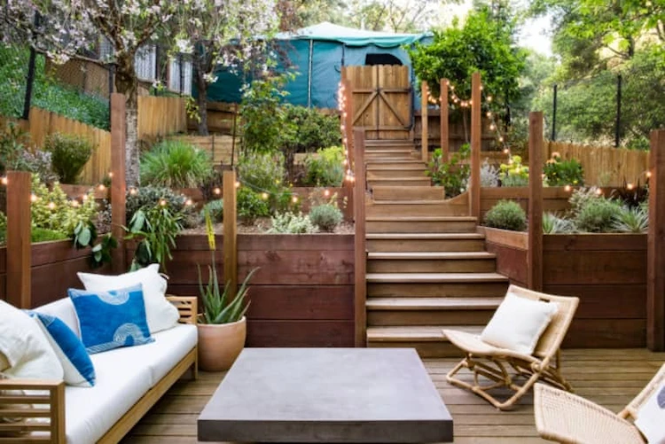 Wooden stairs illuminated with fairy lights in the middle of a terraced garden with a seating area