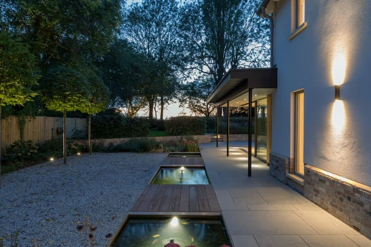 modern outdoor wall lighting with lawn and illuminated garden paths with water feature