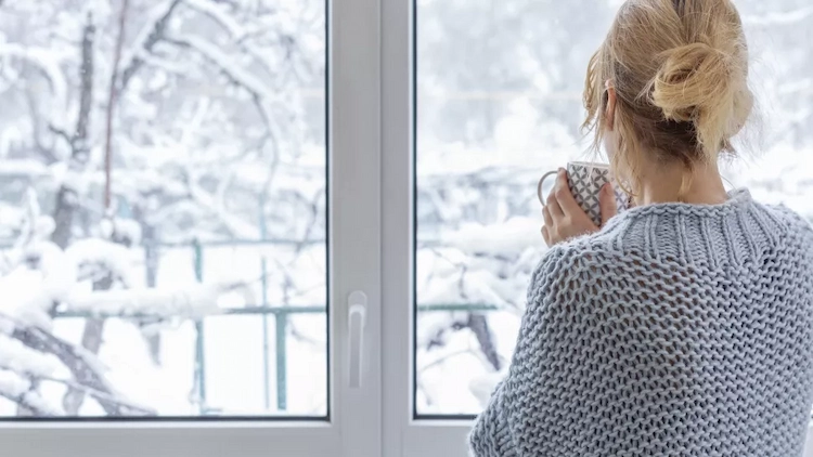 Enjoying the view from the window on a winter day with a warm cup of tea