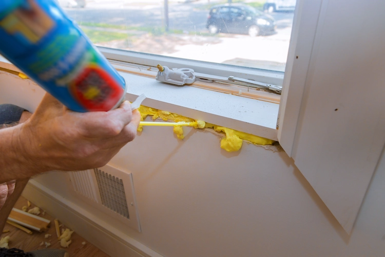 DIYer applies spray foam under windowsill for thermal insulation