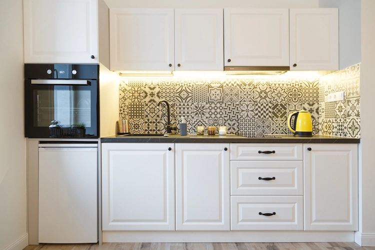 Accent lighting over a back wall that contrasts with white kitchen cabinets